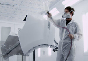 a technician repainting a car part